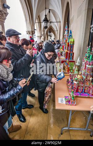 Persone che scattano foto di Szopki (presepi di Natale) all'apertura del concorso annuale a dicembre, evento incluso nella lista dei patrimoni culturali dell'UNESCO, nei portici di Sukiennice (sala dei tessuti), Piazza del mercato principale, Kraków, Polonia Foto Stock