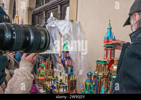 L'artista mette i tocchi finali sul suo Szopka (presepe natalizio) esposto all'apertura del concorso annuale a dicembre, evento incluso nella lista dei patrimoni culturali dell'UNESCO, nei portici di Sukiennice (sala dei tessuti), Piazza del mercato principale, Kraków, Polonia Foto Stock