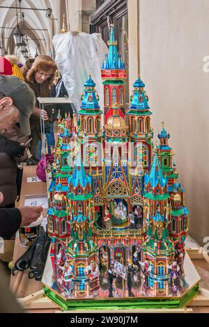 L'artista mette i tocchi finali sul suo Szopka (presepe natalizio) esposto all'apertura del concorso annuale a dicembre, evento incluso nella lista dei patrimoni culturali dell'UNESCO, nei portici di Sukiennice (sala dei tessuti), Piazza del mercato principale, Kraków, Polonia Foto Stock