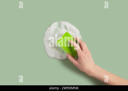 Donna che tiene la spugna di lavaggio mano e detersivo suta Foto Stock
