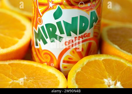 KIEV, UCRAINA - 7 LUGLIO 2023 bevanda all'arancia Mirinda con molte arance fresche su sfondo colorato Foto Stock