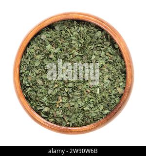 Foglie di coriandolo essiccate, in una ciotola di legno. Foglie di coriandolo, un'erba annuale della famiglia Apiaceae, utilizzata in cucina, con una crostata, gusto di limone. Foto Stock