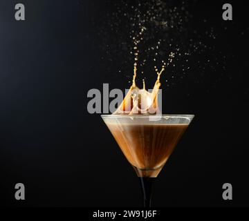 Bevanda espresso Martini con schizzi su sfondo nero. Copia spazio. Foto Stock