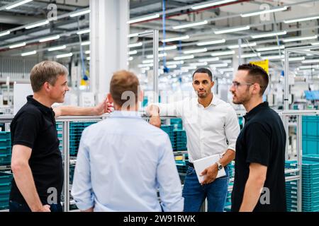 Uomini d'affari e impiegati che hanno una riunione in una fabbrica Foto Stock