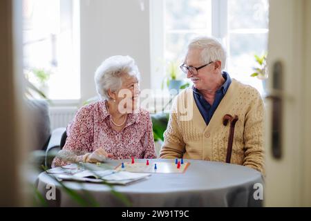 Donna anziana sorridente che gioca a ludo con l'uomo a casa Foto Stock