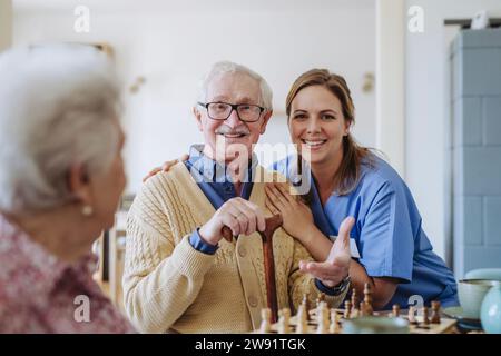 Operatore sanitario sorridente con uomo anziano e donna a casa Foto Stock