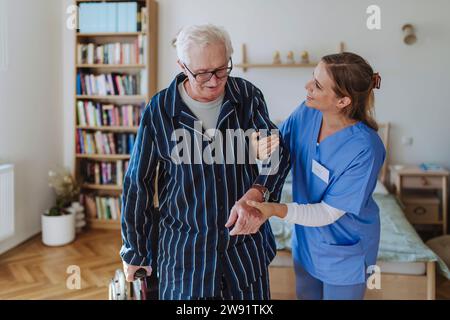 Operatore sanitario sorridente che si prende cura dell'anziano a casa Foto Stock