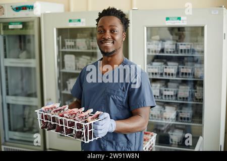 Un tecnico di laboratorio sorridente che tiene le sacche di sangue Foto Stock