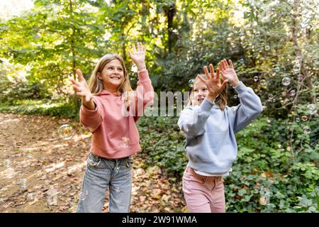 Ragazze felici che giocano con le bolle nel parco Foto Stock