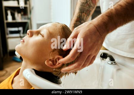 Barbiere che lava i capelli del cliente al salone Foto Stock