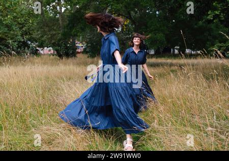 Sorelle gemelle felici che giocano e corrono nel parco Foto Stock