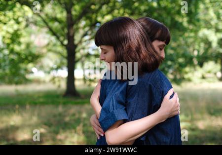 Sorridenti sorelle gemelle che si abbracciano nel parco Foto Stock