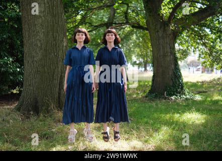 Felici sorelle gemelle che saltano nel parco Foto Stock