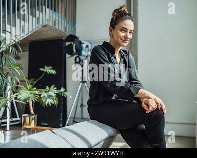 Donna d'affari sorridente seduta sul divano nell'appartamento Foto Stock