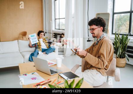 Giovane graphic designer che lavora con un collega in ufficio Foto Stock