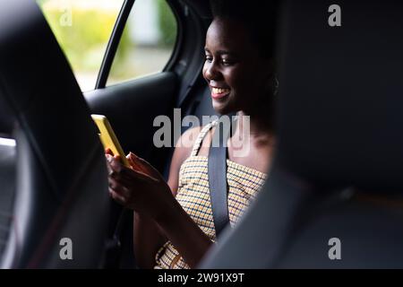 Donna sorridente che usa il telefono cellulare in auto Foto Stock
