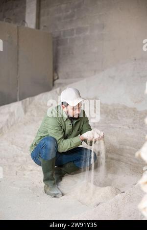 Ritratto di un contadino che si accosta a un mucchio di farina di mais Foto Stock