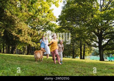 Felici fratelli che si divertono con il cane al parco Foto Stock