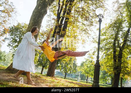Madre che dondola la figlia al parco Foto Stock