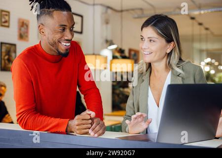 Felici architetti multirazziali che discutono sul laptop al bar Foto Stock