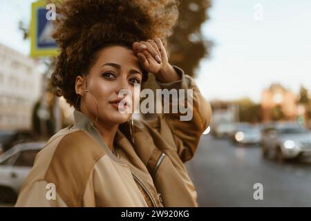 Giovane donna con capelli ricci che tocca la fronte sulla strada Foto Stock