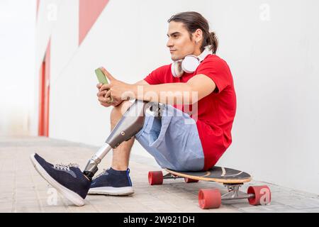 Uomo premuroso con disabilità seduto sullo skateboard Foto Stock