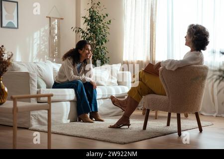 Donna sorridente che si consulta con lo psicologo in salotto a casa Foto Stock