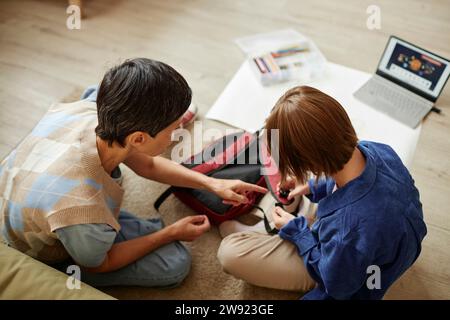 Donna e sua figlia seduti accanto allo zaino sul tappeto a casa Foto Stock