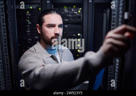 Giovane ingegnere che lavora nella sala server Foto Stock