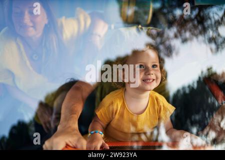 Ragazza sorridente seduta con i genitori in carovana vista attraverso il parabrezza Foto Stock