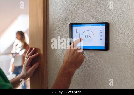 Uomo che regola la temperatura tramite l'app di domotica su tablet PC Foto Stock