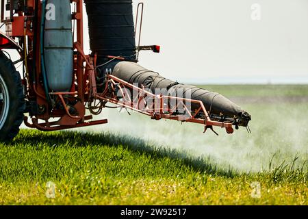 Serbia, provincia della Vojvodina, trattore che spruzza erbicida nei campi di grano primaverili Foto Stock