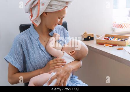 Madre che allatta il neonato con le braccia a casa Foto Stock