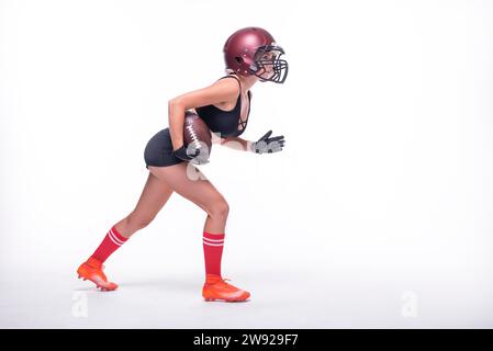 Donna in uniforme di un giocatore della squadra di football americano si prepara a correre con la palla. Sfondo bianco. Concetto sportivo. Supporti misti Foto Stock