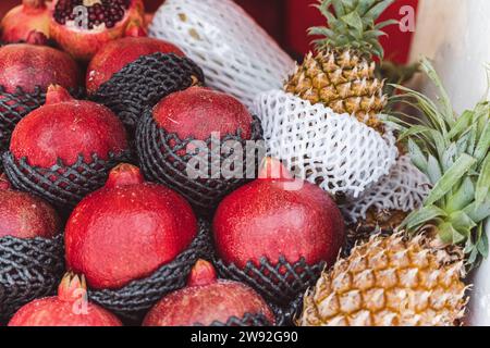 Un'esposizione di melograni e ananas freschi e maturi su uno scaffale pulito, caratterizzato da una varietà di colori e texture vivaci, che creano un'atmosfera accattivante Foto Stock