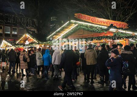 Münster, NRW, Germania. 23 dicembre 2023. Gli amanti dello shopping si fermano per un VIN brulé in uno dei sei mercatini di Natale della città, aperti oggi per l'ultimo giorno. Gli amanti dello shopping e i turisti di Natale passeggiano lungo la graziosa strada medievale Prinzipalmarkt nel centro storico di Münster in un ultimo giorno di shopping piovoso prima della vigilia di Natale. Crediti: Imageplotter/Alamy Live News Foto Stock