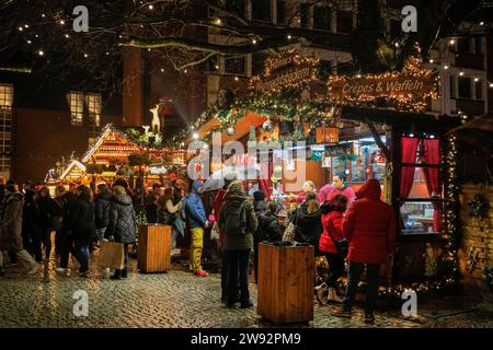 Münster, NRW, Germania. 23 dicembre 2023. Gli amanti dello shopping si fermano per un VIN brulé in uno dei sei mercatini di Natale della città, aperti oggi per l'ultimo giorno. Gli amanti dello shopping e i turisti di Natale passeggiano lungo la graziosa strada medievale Prinzipalmarkt nel centro storico di Münster in un ultimo giorno di shopping piovoso prima della vigilia di Natale. Crediti: Imageplotter/Alamy Live News Foto Stock