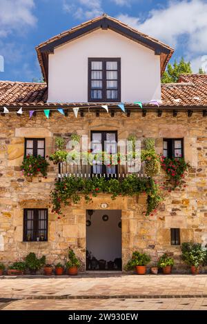 Tipica casa rurale in pietra con un tetto piastrellato e un balcone adornato di fiori. Liérganes, Cantabria, Spagna. Foto Stock