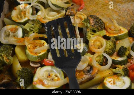 Cibo delizioso, spicchi di patate con verdure sane, anelli di zucchine tritate, anelli di cipolle bianche, pezzi di broccoli, fette di peperone rosso Foto Stock