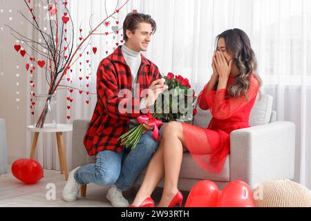 Giovane che propone alla sua ragazza a casa il giorno di San Valentino Foto Stock