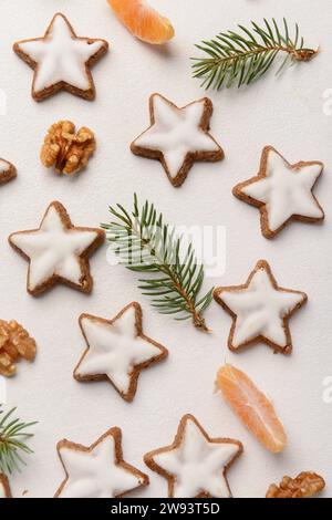 Composizione con deliziosi biscotti natalizi a forma di stelle, mandarino, noci e rami di abete su sfondo chiaro Foto Stock