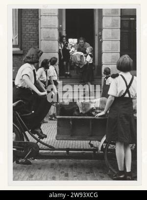 Girls of the Youth Storm Collect Blankets, 1942 - 1944 Fotografia ragazze della tempesta giovanile, in uniforme, raccogliere coperte con una bici da carico per Frontzorg, un'istituzione che ha inviato pakets ai Sser olandesi sul fronte orientale. Fondata nel 1942 da Mussert. Sullo sfondo una ragazza riceve coperte da una signora. Supporto fotografico Paesi Bassi stampa in argento gelatina invio, imballaggio di materiale postale Paesi Bassi Foto Stock