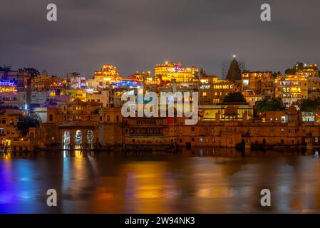 Edificio illuminato e paesaggio urbano intorno al lago Pichola a Udaipur Rajasthan India di notte Foto Stock