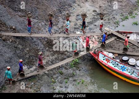 Sirajdikhan, Munshiganj, Bangladesh. 24 dicembre 2023. I lavoratori scaricano il terreno da una barca a Sirajdikhan nel Munisganj, che sarà utilizzata per fare mattoni in un forno. (Immagine di credito: © Syed Mahabubul Kader/ZUMA Press Wire) SOLO USO EDITORIALE! Non per USO commerciale! Crediti: ZUMA Press, Inc./Alamy Live News Foto Stock