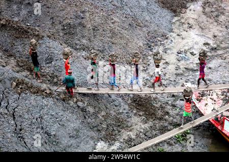 Sirajdikhan, Munshiganj, Bangladesh. 24 dicembre 2023. I lavoratori scaricano il terreno da una barca a Sirajdikhan nel Munisganj, che sarà utilizzata per fare mattoni in un forno. (Immagine di credito: © Syed Mahabubul Kader/ZUMA Press Wire) SOLO USO EDITORIALE! Non per USO commerciale! Crediti: ZUMA Press, Inc./Alamy Live News Foto Stock