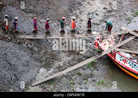 Sirajdikhan, Munshiganj, Bangladesh. 24 dicembre 2023. I lavoratori scaricano il terreno da una barca a Sirajdikhan nel Munisganj, che sarà utilizzata per fare mattoni in un forno. (Immagine di credito: © Syed Mahabubul Kader/ZUMA Press Wire) SOLO USO EDITORIALE! Non per USO commerciale! Crediti: ZUMA Press, Inc./Alamy Live News Foto Stock