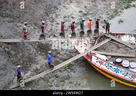 Sirajdikhan, Munshiganj, Bangladesh. 24 dicembre 2023. I lavoratori scaricano il terreno da una barca a Sirajdikhan nel Munisganj, che sarà utilizzata per fare mattoni in un forno. (Immagine di credito: © Syed Mahabubul Kader/ZUMA Press Wire) SOLO USO EDITORIALE! Non per USO commerciale! Crediti: ZUMA Press, Inc./Alamy Live News Foto Stock