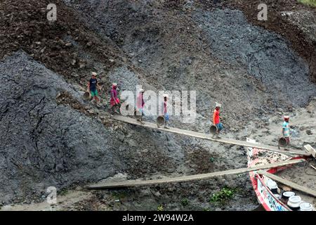 Sirajdikhan, Munshiganj, Bangladesh. 24 dicembre 2023. I lavoratori scaricano il terreno da una barca a Sirajdikhan nel Munisganj, che sarà utilizzata per fare mattoni in un forno. (Immagine di credito: © Syed Mahabubul Kader/ZUMA Press Wire) SOLO USO EDITORIALE! Non per USO commerciale! Crediti: ZUMA Press, Inc./Alamy Live News Foto Stock