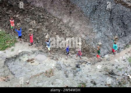 Sirajdikhan, Munshiganj, Bangladesh. 24 dicembre 2023. I lavoratori scaricano il terreno da una barca a Sirajdikhan nel Munisganj, che sarà utilizzata per fare mattoni in un forno. (Immagine di credito: © Syed Mahabubul Kader/ZUMA Press Wire) SOLO USO EDITORIALE! Non per USO commerciale! Crediti: ZUMA Press, Inc./Alamy Live News Foto Stock