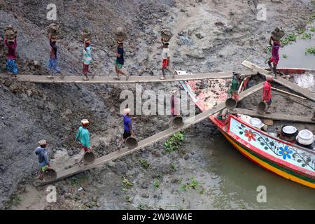 Sirajdikhan, Munshiganj, Bangladesh. 24 dicembre 2023. I lavoratori scaricano il terreno da una barca a Sirajdikhan nel Munisganj, che sarà utilizzata per fare mattoni in un forno. (Immagine di credito: © Syed Mahabubul Kader/ZUMA Press Wire) SOLO USO EDITORIALE! Non per USO commerciale! Crediti: ZUMA Press, Inc./Alamy Live News Foto Stock